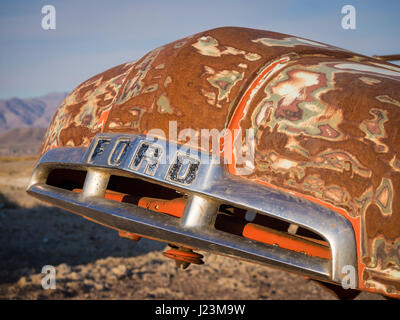 Il cofano di un arrugginito abbandonato Ford pickup truck auto rottamata, lasciato dietro di sé nel deserto. Foto Stock