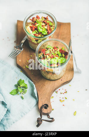 Una sana insalata con quionoa, avocado, pomodori secchi su pannello di legno Foto Stock