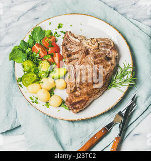 Manzo cotto tbone bistecca con verdure e rosmarino, quadrato ritaglia Foto Stock