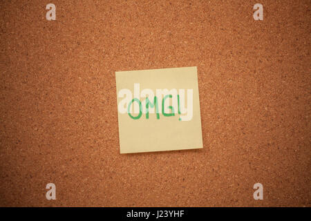 Immagine ravvicinata di una nota di lettura OMG bloccati su una bacheca di sughero. Foto Stock