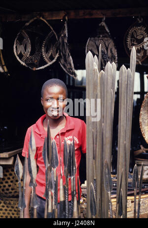 Ragazzo giovane vendendo masai lance e scudi in Mto-Wa-Mbu una piccola città vicino al Lago Manyara National Park, Tanzania Foto Stock