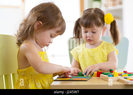 Bambini che giocano con il giocattolo logico sulla scrivania in nursery room o asilo nido. Disponendo i bambini e lo smistamento di forme, colori e dimensioni. Foto Stock