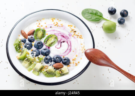 Vegane di yogurt con frutti di bosco freschi e frutta e superfoods nella ciotola sul tavolo bianco Foto Stock