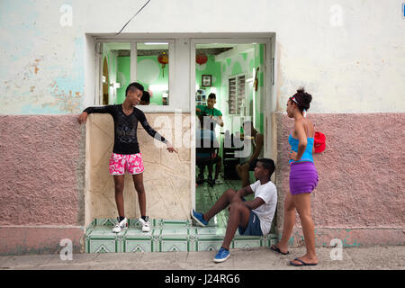 I giovani cubani appendere fuori davanti a un negozio di barbiere a l'Avana, Cuba. Foto Stock