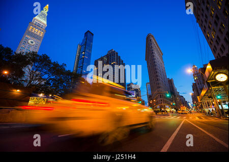 Il traffico che passa in motion blur in una luminosa vista serale delle strade di New York City al Madison Square, dove Fifth Avenue e Broadway si intersecano Foto Stock