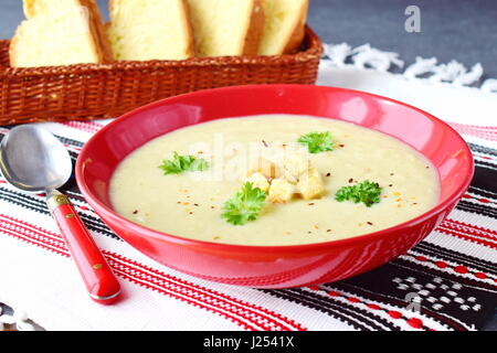 Creme di verdure con cavolfiore e crema in un rosso coppa in ceramica su un sfondo di materie tessili. Mangiare sano concetto. Foto Stock