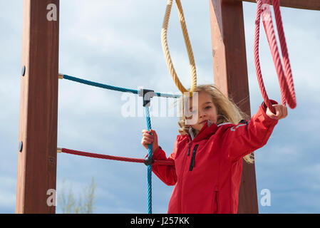 Infanzia, il tempo libero e il concetto di persone - happy bambina su giochi per bambini arrampicata Foto Stock