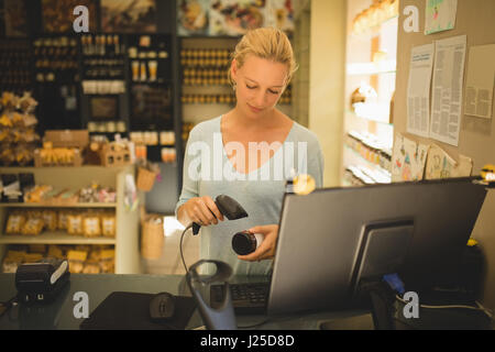 Giovane commessa prodotto di scansione in negozio Foto Stock