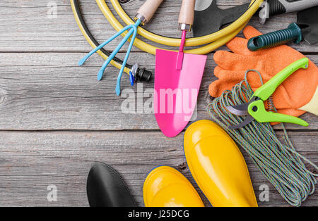 Stivali di gomma e attrezzi da giardino. Ancora vita su tavole di legno. Foto Stock