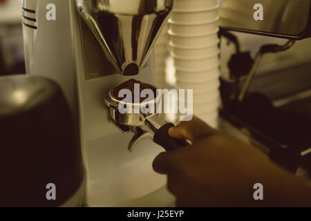 Mano del barista azienda portafilter sotto la macchina per caffè nella caffetteria Foto Stock