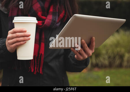 Sezione mediana della donna azienda tablet e la tazza di caffè Foto Stock