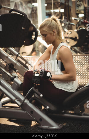 Montare donna utilizzando smartwatch su una macchina in palestra Foto Stock