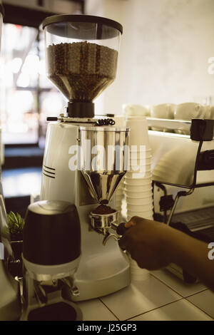 Mano del barista azienda portafilter sotto la macchina per caffè nella caffetteria Foto Stock