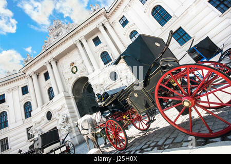 Ampio angolo di vista del famoso Palazzo di Hofburg con tradizionale a cavallo il Fiaker carrelli in una giornata di sole a Vienna, in Austria Foto Stock