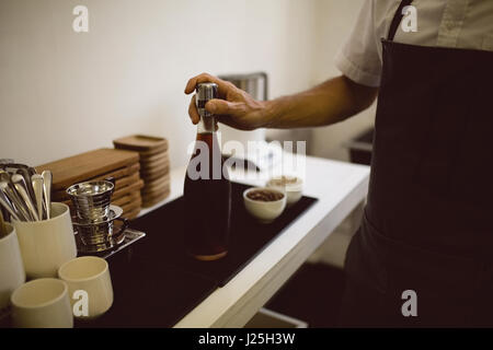 Barista maschio tenendo la bottiglia piena di caffè nero in coffee shop Foto Stock