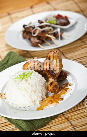 Un colpo di pollo al curry piatto e carne di maiale satay su piastre bianche Foto Stock