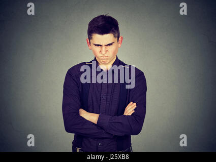 Arrabbiato grumpy man looking molto dispiaciuto isolato sul muro grigio Sfondo. Negative le emozioni umane espressione facciale Foto Stock