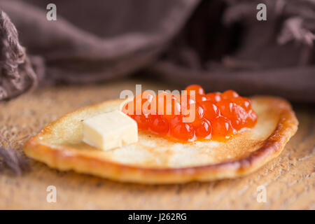 Tradizionale russo pancake con caviale rosso su uno sfondo di legno Foto Stock