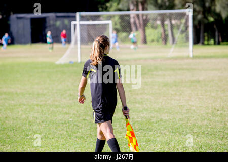 Ragazza donna linesman assistente arbitro a una partita di calcio maschile a Sydney, tra le squadre della lega Manly Warringah Foto Stock