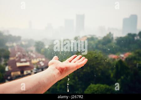 Giorno di pioggia nella città. Gocce di pioggia caduta sulla mano. Kuala Lumpur in Malesia Foto Stock