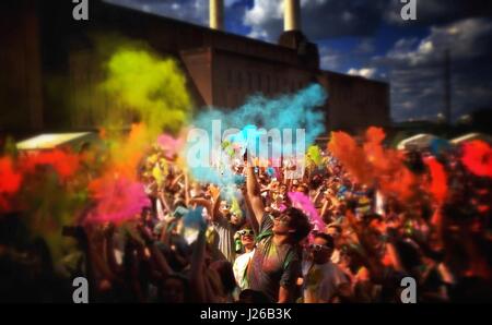 La gente di gettare polvere colorata in aria a Holi festival, Battersea Power Station di Londra, Inghilterra, Regno Unito Foto Stock