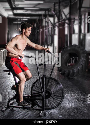 Giovane atleta con cyclette in palestra. Fitness utilizzando maschio Foto Stock