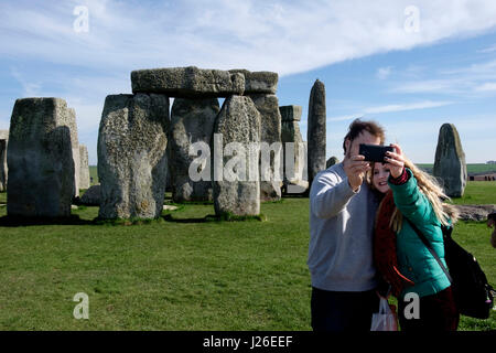 Giovane donna prendendo un selfie con il loro smartphone davanti a Stonehenge il monumento preistorico nel Wiltshire, Inghilterra Foto Stock