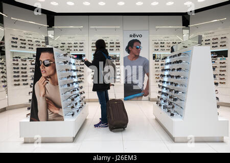 Donna con bagagli shopping per occhiali da sole al tax free store in un aeroporto Foto Stock