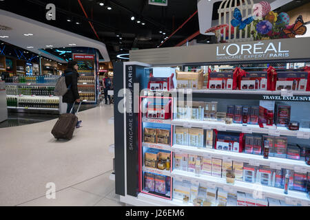 Passeggeri con valigia camminare da un L'Oréal stand al duty free store, dall'aeroporto di Portela di Lisbona, Portogallo, Europa Foto Stock