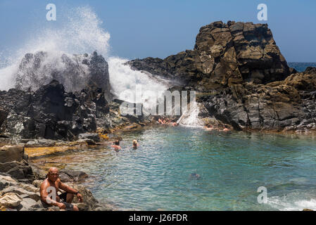 Un'onda esplode sulle pareti della Conchi piscina naturale, Aruba Foto Stock