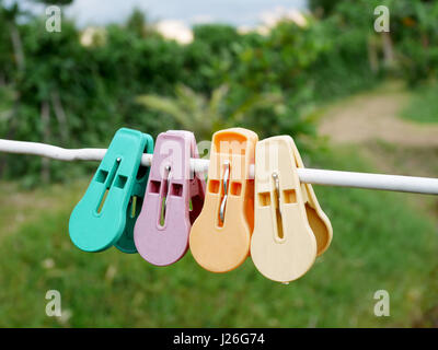 Abbigliamento colorato pioli o clothespins appeso sulla corda bianca in giardino alla campagna della Thailandia Foto Stock