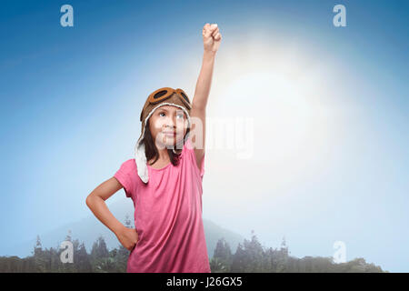 Asian sorridente bambina in aviatore casco sogna di diventare un pilota nel parco Foto Stock