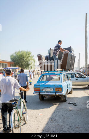 MARGILAN, Uzbekistan - 21 agosto: persone che trasportano divano sul tetto della vecchia Lada sovietica auto dal bazaar Kumtepa. Agosto 2016 Foto Stock