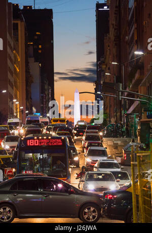 Il traffico su Avenida Corrientes al tramonto, con l'Obelisco in background. Buenos Aires, Argentina. Foto Stock