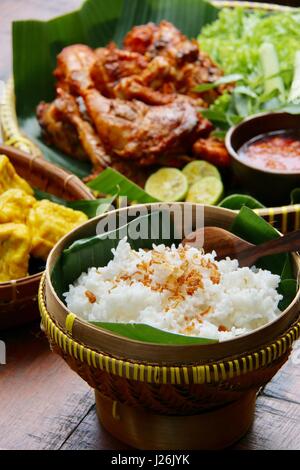 Riso al vapore in un tradizionale cestello di bambù, piatto di lato indonesiani pollo alla brace Foto Stock