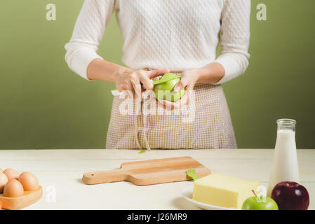 Casa moglie indossando il grembiule. Fasi di Realizzazione di cottura di torta di mele. Il taglio di mela verde. Foto Stock