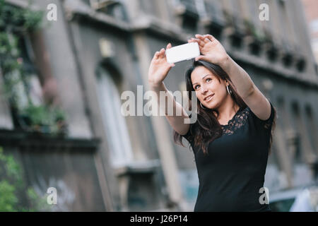 Felice bella giovane donna prendendo un selfie con il suo smart phone. Foto Stock