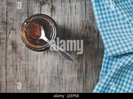 Cucchiaio e il vasetto di vetro di marmellata sul vecchio tavolo in legno. Tonica foto. Foto Stock