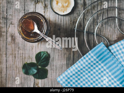 Cucchiaio e il vasetto di vetro di marmellata sul vecchio tavolo in legno. Tonica foto. Foto Stock