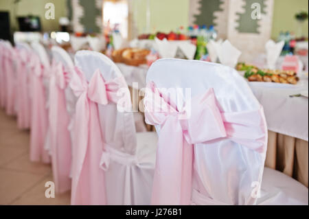 Sedie con fiocco rosa in sala per matrimoni. Foto Stock