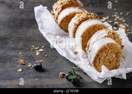 Set di gelato fatto in casa panini in oat i biscotti con zucchero di mandorla briciole, mirtilli e menta sulla carta da forno su metallo scuro dello sfondo texture. Foto Stock