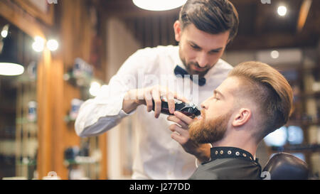 Giovane uomo nel negozio di Barbiere per la cura dei capelli il concetto di servizio Foto Stock