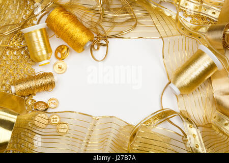 Studio shot di oro elementi di cucitura, bottoni, nastri, il filo isolato su uno sfondo bianco. Foto Stock