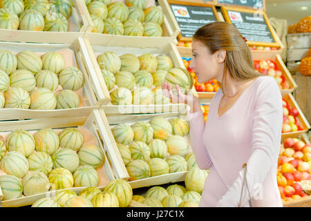 Signora odore di melone al negozio di generi alimentari Foto Stock