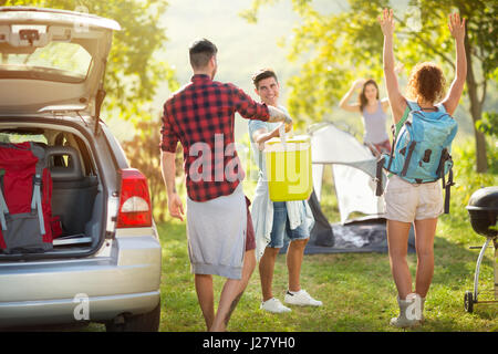 Gruppo di amici felice disimballaggio auto per viaggio di campeggio Foto Stock