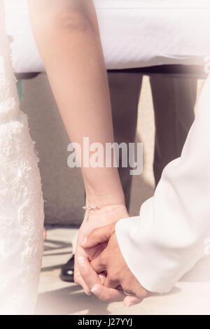 Close up della sposa e lo sposo tenendo le mani durante la cerimonia di matrimonio Foto Stock