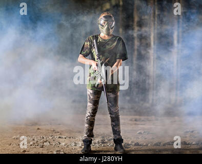 Lettore di paintball in camuffamento di protezione uniforme e maschera con pistola di marcatore per esterno Foto Stock