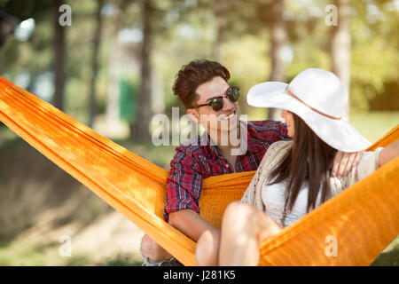 Giovane ragazzo abbracciando bella ragazza in arancione amaca in foresta Foto Stock