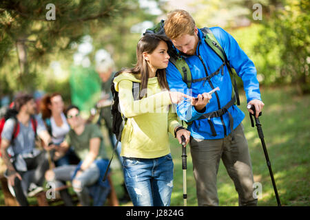 Ragazzo e ragazza guarda la mappa su una pausa nel verde della foresta Foto Stock