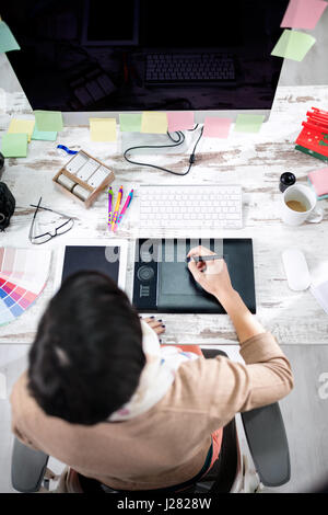 Donna designer iscritto sulla tabella di penne in ufficio vista superiore Foto Stock